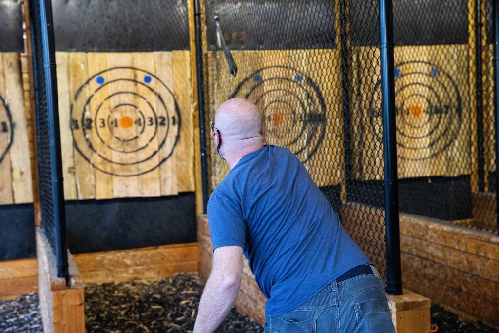man with blue t shirt throwing axe at axe throwing venue